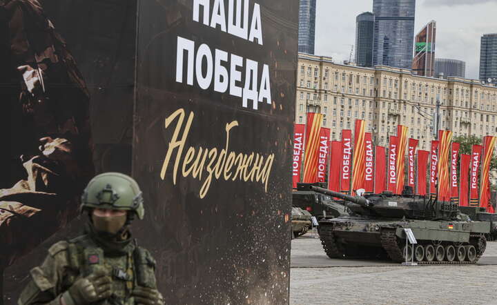 Moskwa: przygotowania do pokazu sprzętu zdobytego na ukraińskim froncie. Rosyjski żołnierz stoi na tle baneru z hasłem: "Nasze zwycięstwo nieuniknione"  / autor: SERGEI ILNITSKY/EPA/PAP
