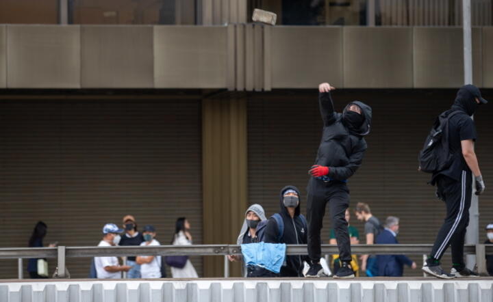 A protester throws a brick on to a road to stop traffic in the business district / autor: EPA/JEROME FAVRE / EPA / PAP