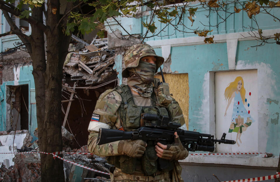 Zdjęcie wykonane podczas wizyty w Mariupolu zorganizowanej przez rosyjskie wojsko przedstawia rosyjskiego żołnierza na warcie przed szkołą nr 22, uszkodzoną w wyniku ostrzału 30 maja w centrum Doniecka na Ukrainie. / autor: PAP/EPA