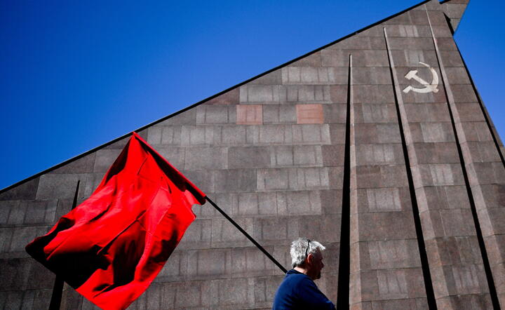 Mężczyzna idzie z czerwoną flagą pod sowieckim pomnikiem II wojny światowej w parku Treptow, Berlin, Niemcy, 8 maja 2023 r. II wojna światowa zakończyła się bezwarunkową kapitulacją nazistowskich Niemiec na wszystkich frontach 9 maja / autor: EPA/PAP
