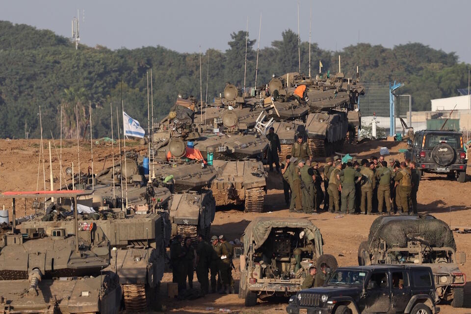Izraelscy żołnierze zbierają się w pobliżu czołgów na pozycji w pobliżu granicy ze Strefą Gazy, w południowym Izraelu / autor: PAP/EPA/ATEF SAFADI