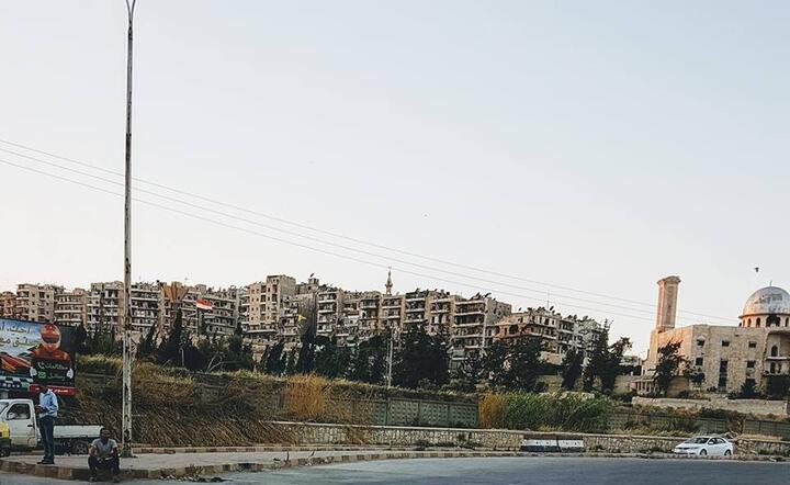 Widok na kurdyjską dzielnicę Sheikh Maqsoud w Aleppo. Na prawo od flagi syryjskiej można dostrzec flagi kurdyjskich milicji YPG i YPJ / autor: fot. Jakub Szyszko