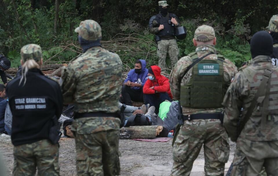 Grupa uchodźców i straż graniczna w pobliżu miejscowości Usnarz Górny  / autor: PAP/Artur Reszko