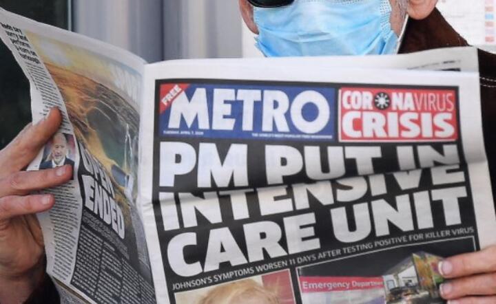 Mężczyzna w masce ochronnej czyta wiadomości o stanie brytyjskiego premiera Borisa Johnsona przed szpitalem St.Thomas 'w Londynie, 7 kwietnia 2020 r. / autor: PAP/EPA/ANDY RAIN