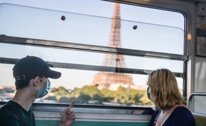 Osoby dojeżdżające do pracy noszą ochronne maski, w pociągu spoglądają na Wieżę Eiffla w Paryżu. / autor: PAP/EPA/MOHAMMED BADRA