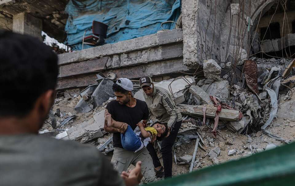 Przesiedleni Palestyńczycy niosą rannego chłopca po izraelskim nalocie w mieście Gaza w północnej części Strefy Gazy / autor: PAP/EPA/MOHAMMED SABER