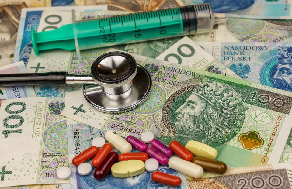 Zdjęcie ilustracyjne przedstawiające stetoskop, pieniądze, tabletki oraz strzykawkę / autor: Fratria