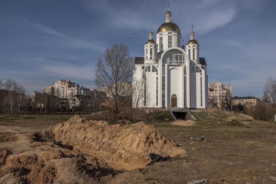 Na zdjęciu masowe groby w Buczy, naprzeciw prawosławnej cerkwii / autor: PAP/EPA