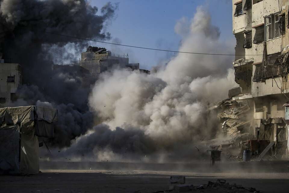 Dym nad budynkiem Al Harazin po ataku lotniczym podczas izraelskiej operacji wojskowej w mieście Gaza / autor: PAP/EPA