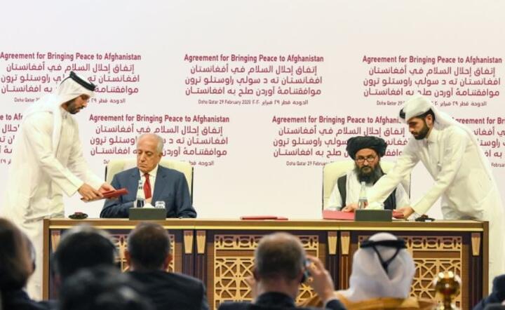 Specjalny przedstawiciel ds. Pojednania w Afganistanie Zalmay Khalilzad (2-L) i współzałożyciel talibów Mullah Abdul Ghani Baradar (2-R) podpisują porozumienie pokojowe między USA a talibami podczas ceremonii w Doha, Katar, 29 lutego 2020 r. / autor: PAP/EPA/STRINGER