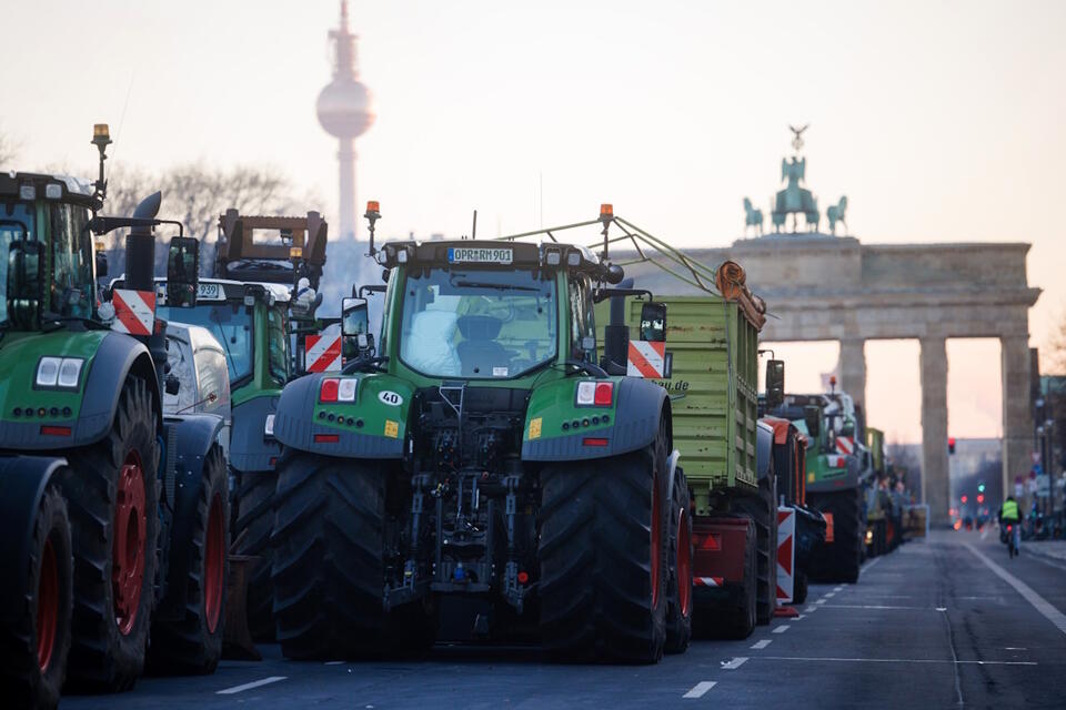 Traktory stoją w kolejce przed Bramą Brandenburską na tle wieży telewizyjnej podczas ogólnokrajowego strajku rolników w Berlinie / autor: PAP/EPA/CLEMENS BILAN