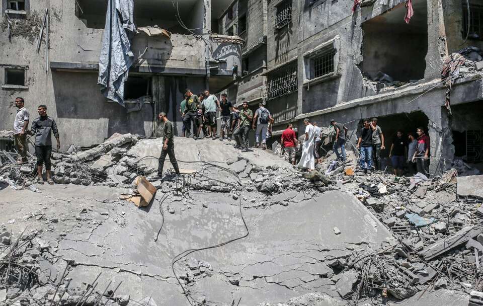 Palestyńczycy szukają ciał i ocalałych wśród gruzów zniszczonego domu po izraelskim nalocie w mieście Gaza / autor: PAP/EPA/MOHAMMED SABER