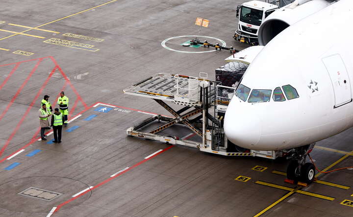 Pracownicy lotniska przy uziemionym samolocie na lotnisku Berlin Brandenburg  / autor: PAP/EPA/FILIP SINGER