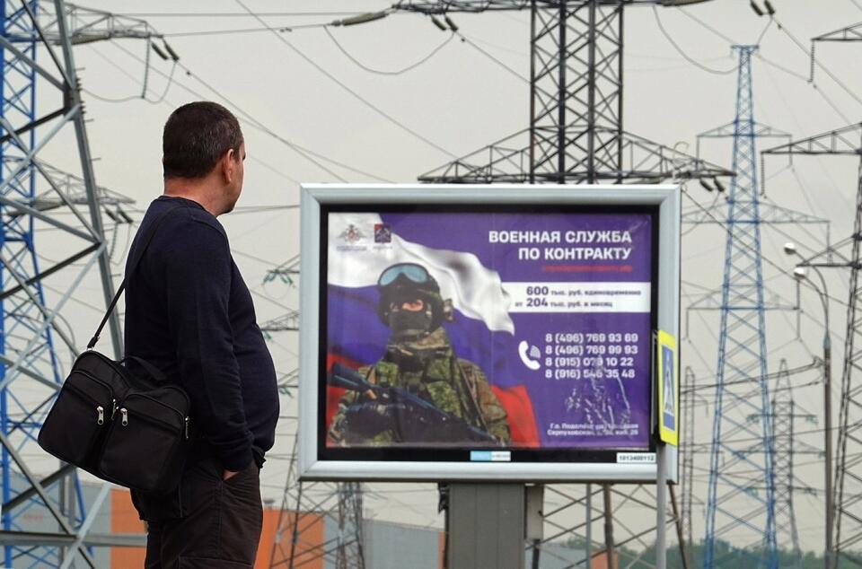 Mężczyzna stoi przed billboardem wspierającym rosyjskie siły zbrojne z napisem 'Służba kontraktowa' pod Moskwą / autor: PAP/EPA