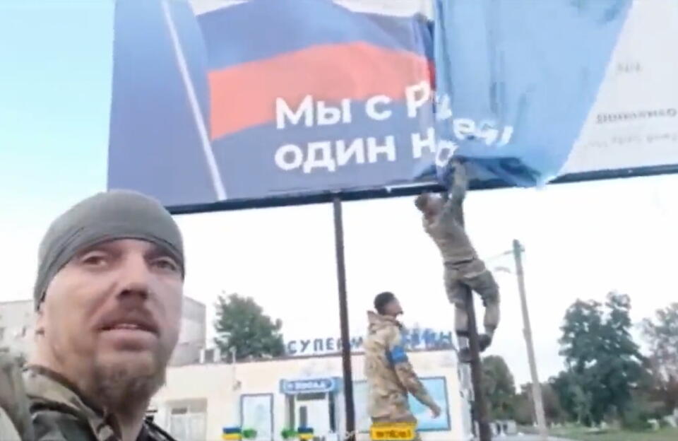 Ukraińscy żołnierze zrywający rosyjski plakat propagandowy  / autor: screenshot video TT