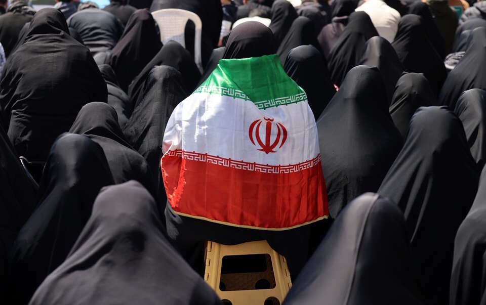 Na zdjęciu osoba owinięta we flagę Iranu pośród uczestników na placu Enghelab po ogłoszeniu zawieszenia broni przez USA i Iran w Teheranie / autor: PAP/EPA