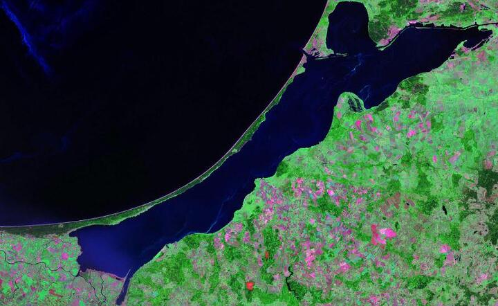 Mierzeja Wiślana, zdjęcie satelitarne za: "Vistula Lagoon". Licencja: Domena publiczna na podstawie Wikimedia Commons - https://commons.wikimedia.org/wiki/File:Vistula_Lagoon.jpg#/media/File:Vistula_Lagoon.jpg