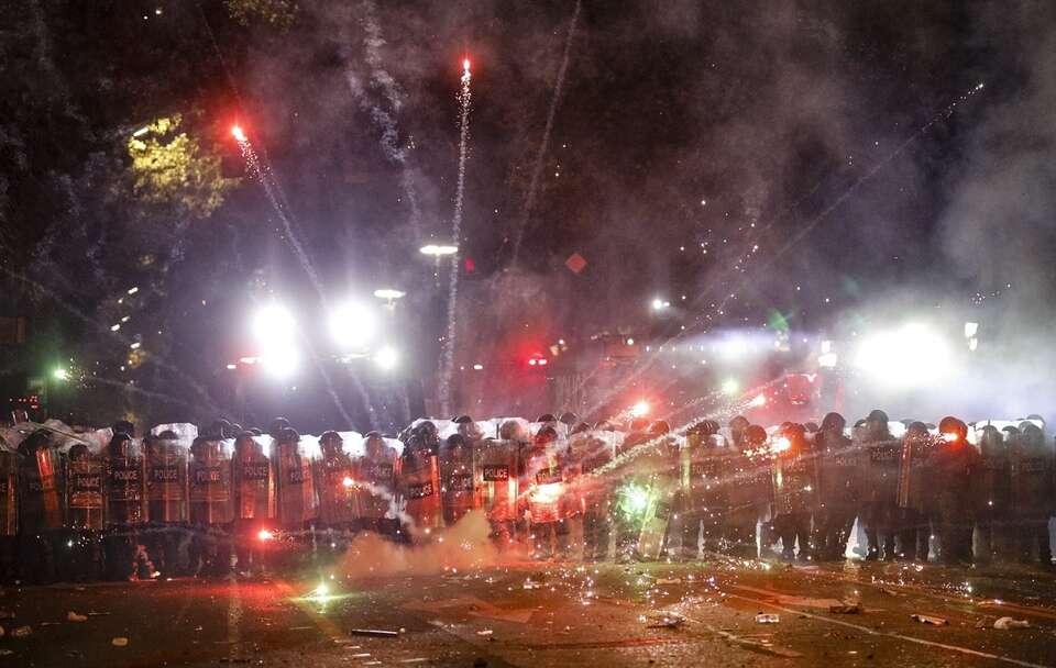 Zwolennicy gruzińskiej opozycji odpalają fajerwerki w kierunku policji podczas protestu przed budynkiem parlamentu w Tbilisi / autor: PAP/EPA