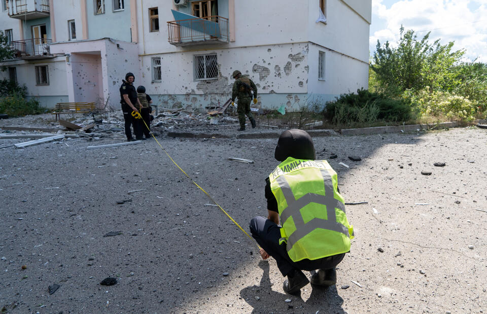 Ekspert szuka fragmentów rosyjskiego pocisku, który zniszczył jeden z bloków mieszkalnych Charkowie. / autor: PAP/Mykola Kalyeniak
