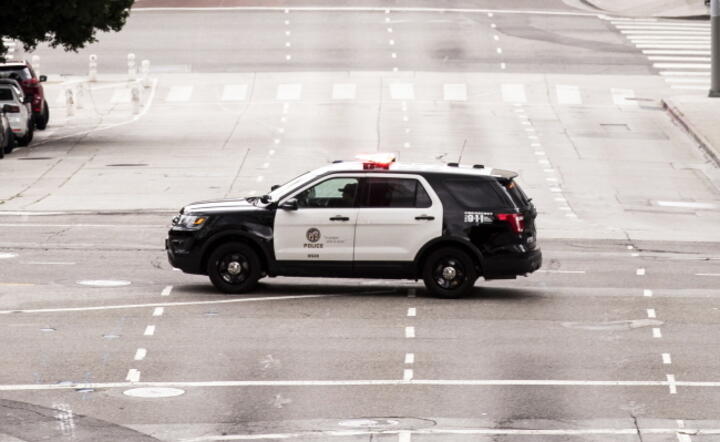 Policyjny wóz na opustoszałym skrzyżowaniu w centrum Los Angeles, Kalifornia, USA / autor: PAP/EPA/ETIENNE LAUREN
