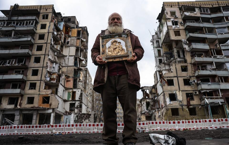 Starszy mężczyzna z ikoną w rękach przed zniszczonym blokiem w Dnieprze / autor: PAP/Leszek Szymański