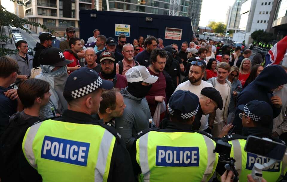 Funkcjonariusze policji powstrzymują protestujących przed hotelem Britannia, w którym mieszkają osoby ubiegające się o azyl, podczas demonstracji w Londynie / autor: PAP/EPA/NEIL HALL