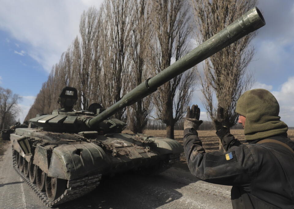 Ukraiński wojskowy steruje zdobytym rosyjskim czołgiem / autor: PAP/EPA