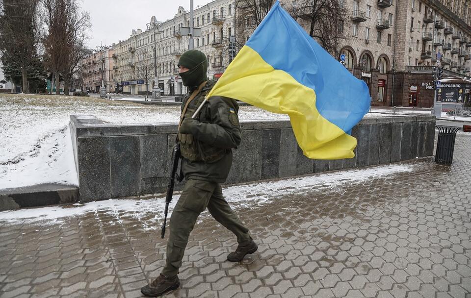 Ukraiński żołnierz niesie przez Kijów flagę państwową / autor: PAP/EPA