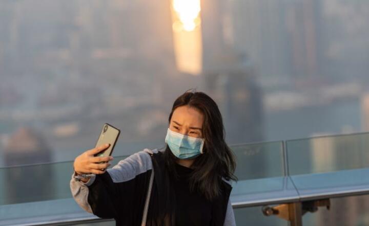 Kobieta w masce na panoramicznym tarasie widokowym na szczycie w Hongkongu w Chinach / autor: PAP/EPA/JEROME FAVRE