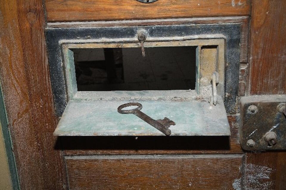 „Okienko” w drzwiach do jednego z pomieszczeń (dawnej celi) w piwnicy w dawnej siedzibie więzienia UB w Pułtusku / autor: Materiały prasowe