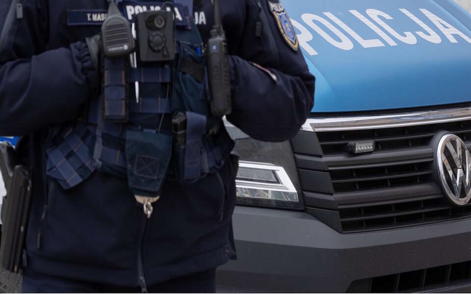 Policjant stoi na tle radiowozu / autor: Fratria