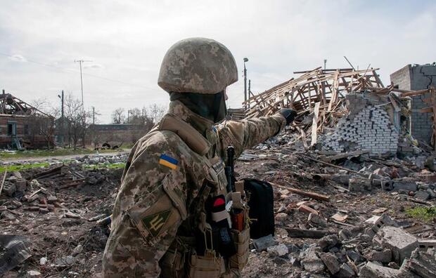 Ukraiński żołnierz na tle zniszczonych przez rosyjskie bombardowanie budynków w miasteczku Czuhujiw (obw. charkowski) / autor: PAP/Mykola Kalyeniak