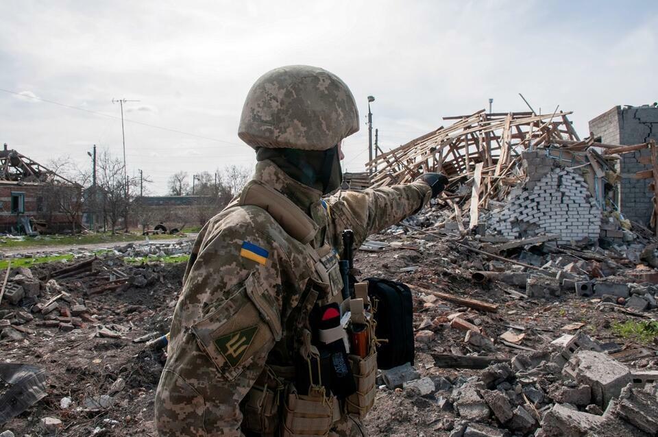 Ukraiński żołnierz na tle zniszczonych przez rosyjskie bombardowanie budynków w miasteczku Czuhujiw (obw. charkowski) / autor: PAP/Mykola Kalyeniak