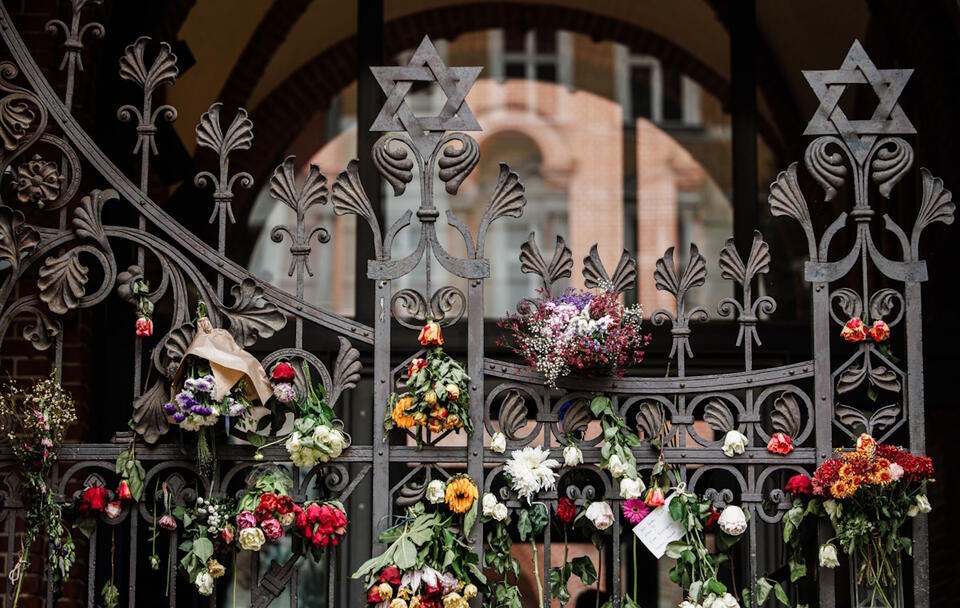 Kwiaty wiszą na żelaznej bramie synagogi Rykestrasse w reakcji na trwający konflikt zbrojny w Izraelu, w Berlinie, Niemcy / autor: PAP/EPA/CLEMENS BILAN