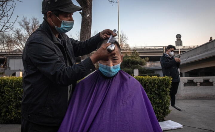 Fryzjer pod gołym niebem na ulicy Pekinu / autor: PAP/EPA/ROMAN PILIPEY