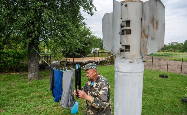 Mykoła Krawczenko rozwiesza pranie na sznurze, przymocowanym do fragmentu rosyjskiej rakiety, 30 bm. we wsi Majdaniwka w obwodzie kijowskim. / autor: PAP/Vladyslav Musiienko