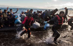 Nielegalni migranci świętują przybycie przeciążonym gumowym pontonem na wybrzeże w pobliżu Skala Sikaminias na wyspie Lesbos w Grecji / autor: PAP/EPA
