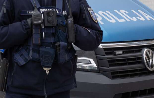 Policjant na tle radiowozu / autor: Fratria