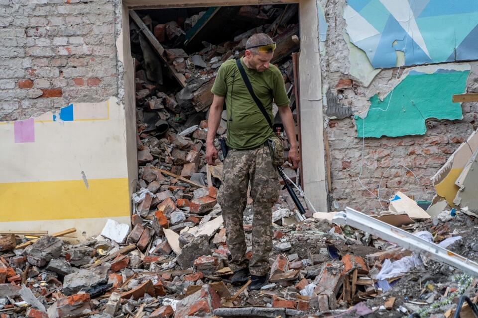 Żołnierz wojsk Ukrainy na gruzach zniszczonej w wyniku rosyjskiego ataku rakietowego szkoły w obwodzie charkowskim. / autor: PAP/Mykola Kalyeniak