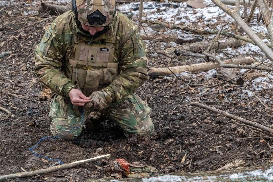  Ekspert ds. usuwania bomb ze Służby Materiałów Wybuchowych Głównego Zarządu Policji Narodowej Ukrainy oczyszczają i rozminowują pas lasu w obwodzie charkowskim. / autor: PAP/Mykola Kalyeniak