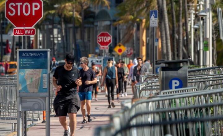 Turyści spacerują wzdłuż zamkniętej plaży w Miami Beach w South Beach na Florydzie, USA. / autor: PAP/EPA/CRISTOBAL HERRERA