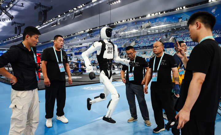 Chińscy "trenerzy" humanoidalnego robota startującego w światowych igrzyskach w Pekinie / autor: PAP/EPA/WU HAO