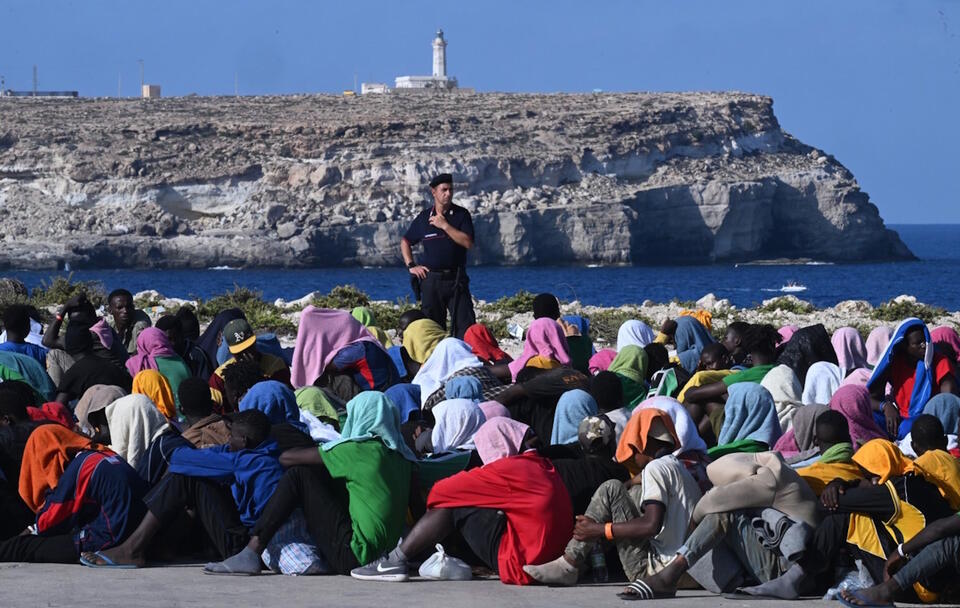 Migranci czekają w Cala Pisana na przeniesienie w inne miejsca z wyspy Lampedusa na południu Włoch / autor: PAP/EPA/CIRO FUSCO