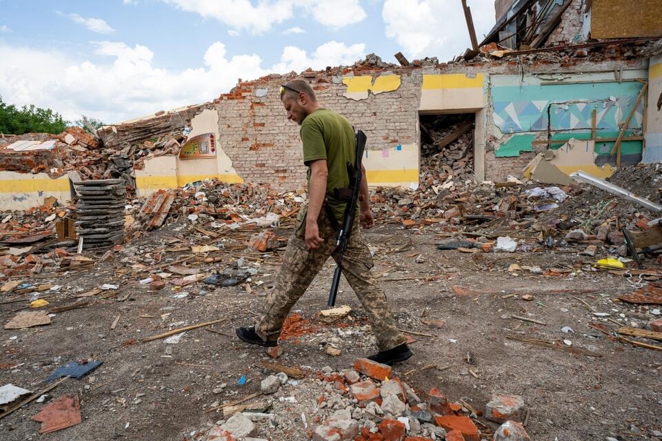 Żołnierz wojsk Ukrainy na gruzach zniszczonej w wyniku rosyjskiego ataku rakietowego szkoły w obwodzie charkowskim. / autor: PAP/Mykola Kalyeniak